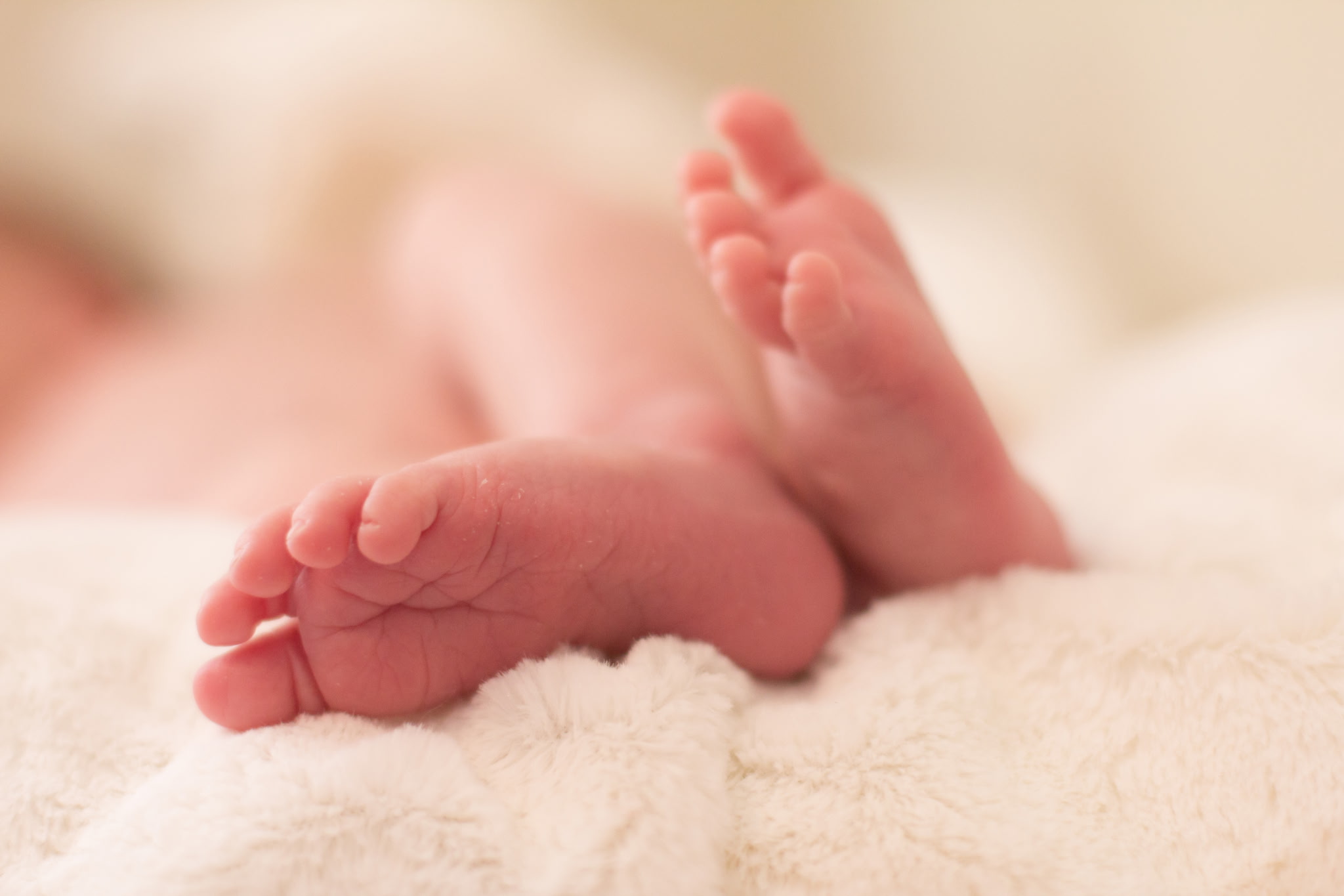 Newborn baby feet resting on a soft blanket