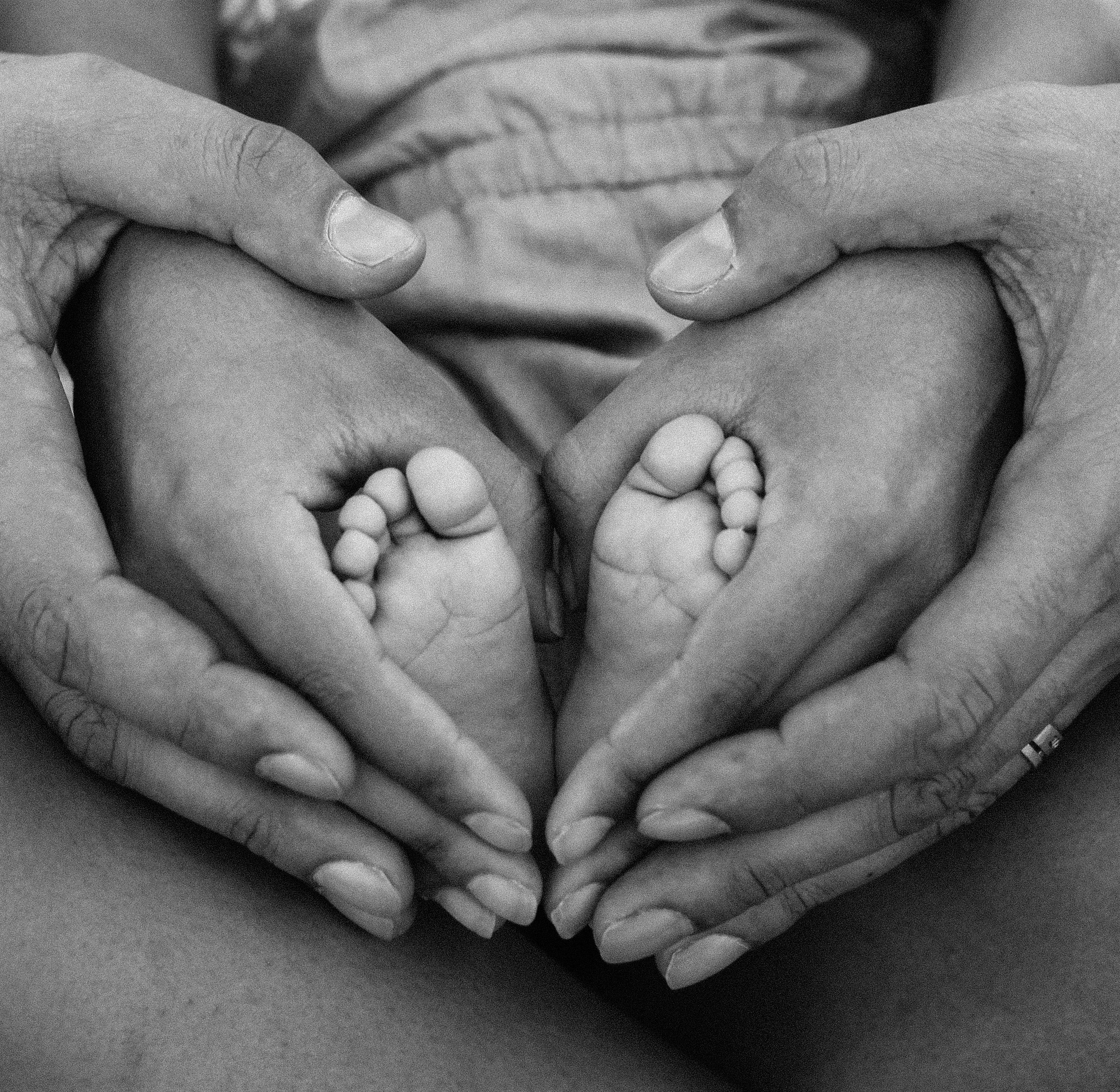 Tiny baby feet cradled in loving hands